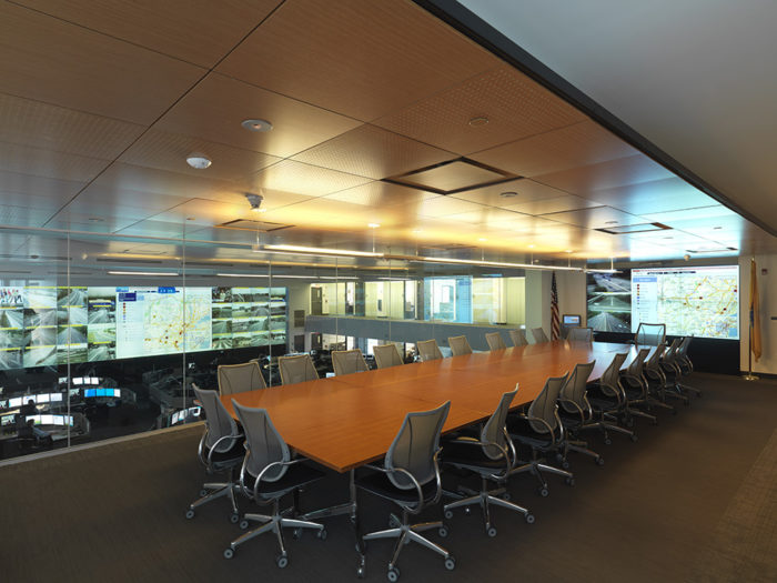 Pictured: A conference room with a flatscreen display, adjacent to a control room and video wall.